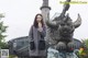 A woman standing in front of a statue of a dragon.