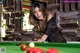 A woman leaning over a pool table with a cue.