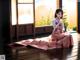 A woman in a pink dress sitting on a wooden floor.