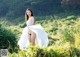 A woman in a white dress standing in a field.