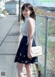 A woman in a white top and blue skirt posing for a picture.