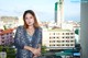 A woman standing on a balcony with a city in the background.