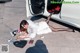 A woman laying on the ground next to a white car.