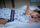 A woman laying on a bed in a blue and white pajamas.