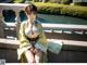 A woman in a green and yellow kimono sitting on a bridge.