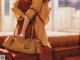 A woman in a yellow kimono holding a brown bag.